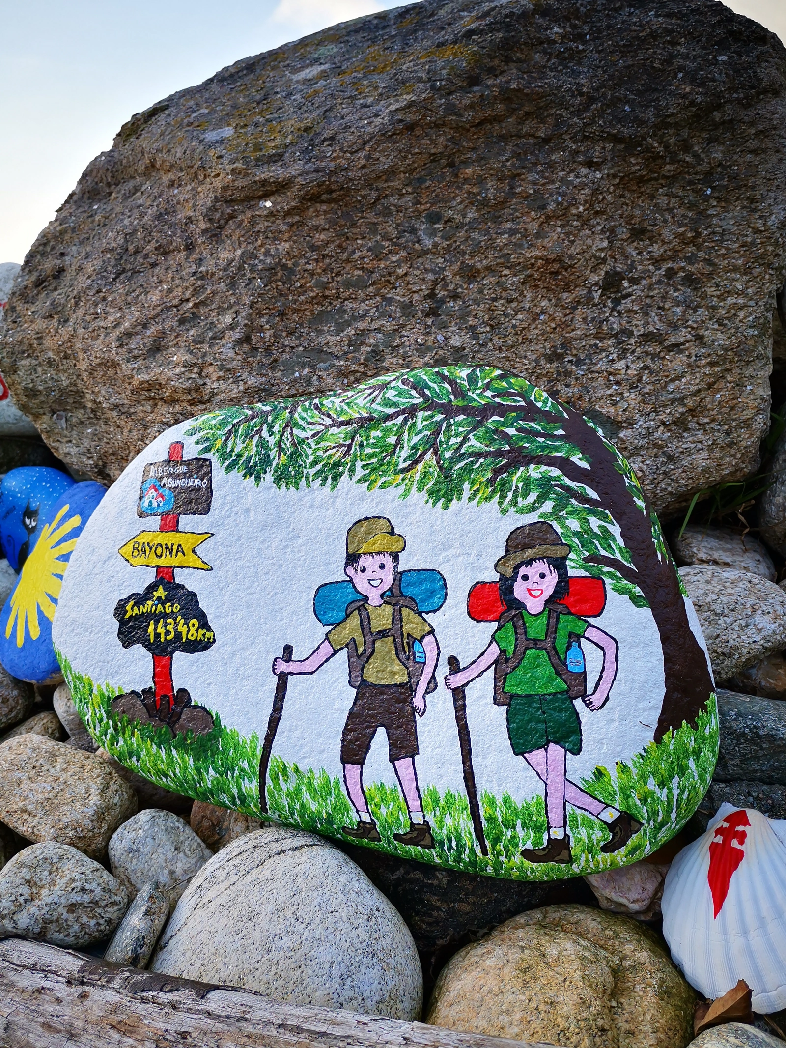Piedra de Mougás decorada con dos peregrinos y una flecha amarilla